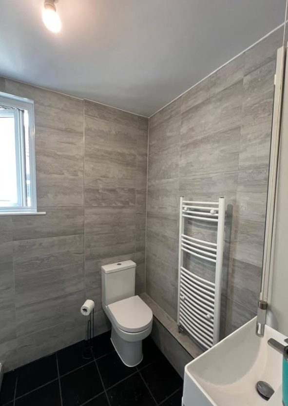 Renovated bathroom with grey tiling and towel radiator